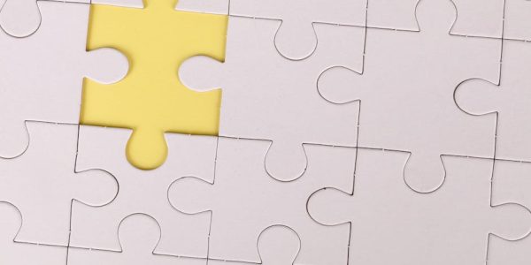 pexels-photo-3482442-3482442 Close-up of a white jigsaw puzzle with a single yellow piece missing, symbolizing incompleteness.